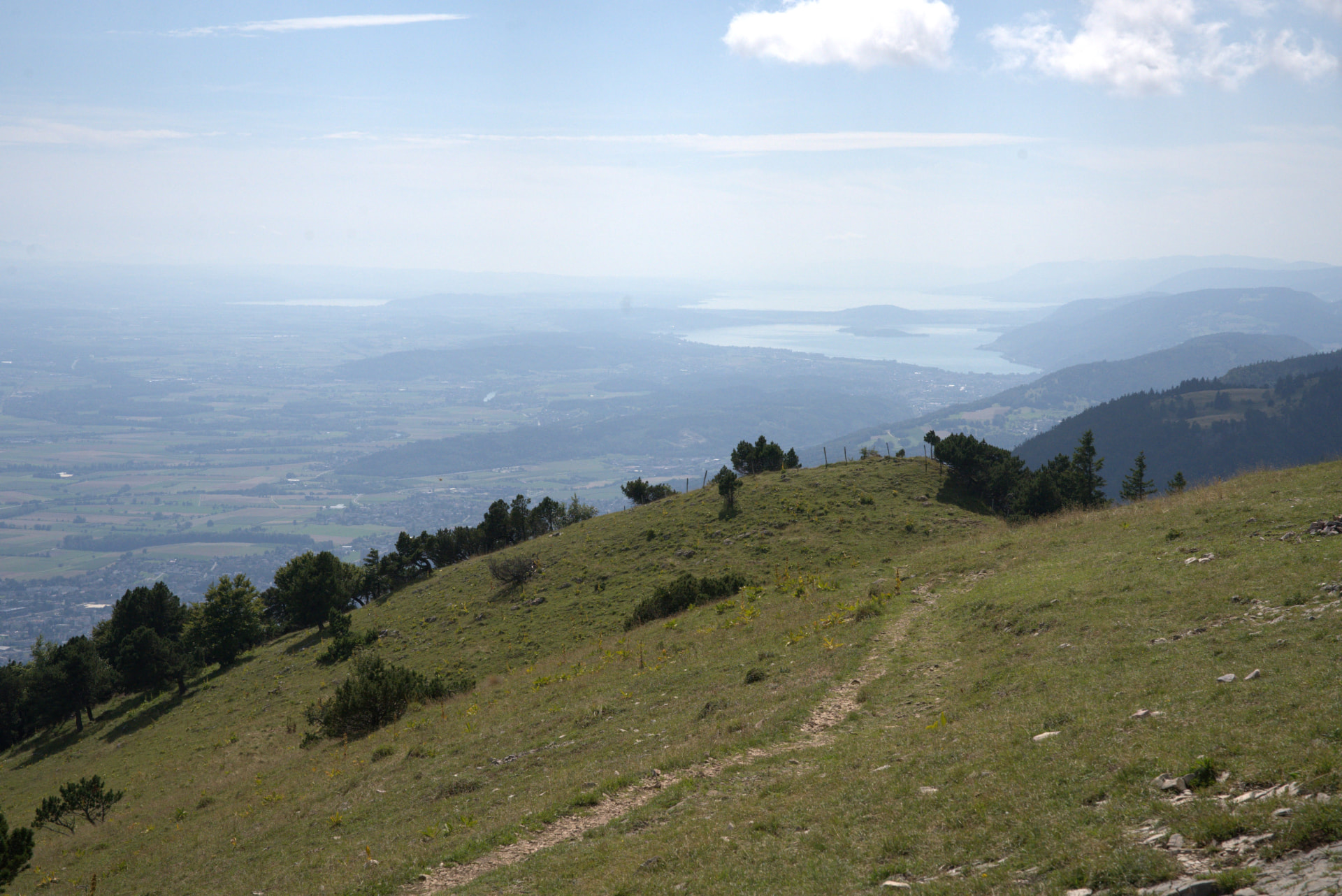 Berglandschaft mit Weg, Hügeln und See im Hintergrund